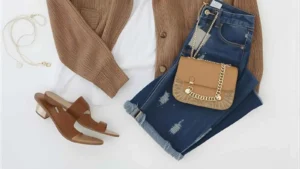 Stylish flatlay of a chic outfit with accessories, shoes, and a coffee cup on a neutral background.